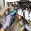 Electrician engineer tests electrical installations and wires on relay protection system. Adjustment of scheme of automation and control of electrical equipment.